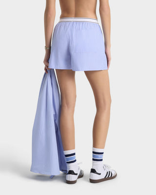 Person wearing light blue shorts with a white background