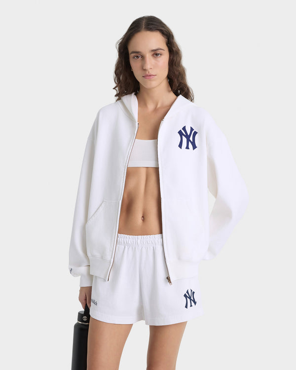 Woman wearing a white hoodie and shorts with a logo on a white background