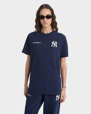 Person wearing a navy blue t-shirt with logos on a white background