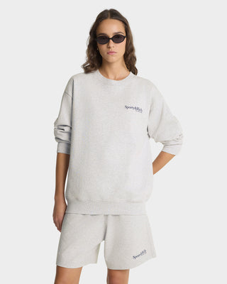 Woman wearing a gray sweatshirt and shorts set with 'Supreme' logo on a white background