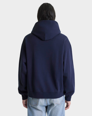 Person wearing a navy blue hoodie from behind on a light gray background