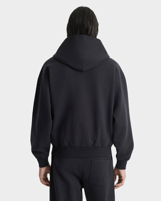 Person wearing a black hoodie from behind on a light gray background