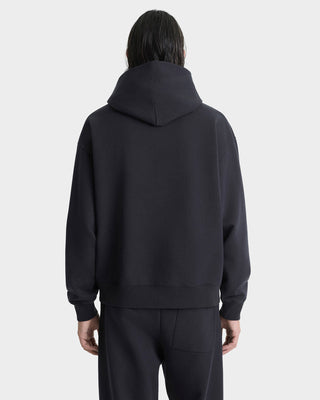 Person wearing a black hoodie and pants on a white background