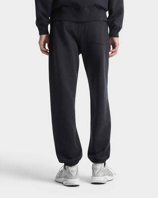 Person wearing black sweatpants and a matching top on a white background