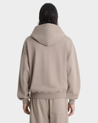 Person wearing a beige hoodie and pants on a white background