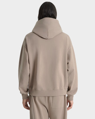 Person wearing a beige hoodie and pants on a white background