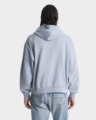 Person wearing a light gray hoodie and light blue jeans on a white background