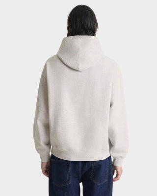 Person wearing a beige hoodie on a white background