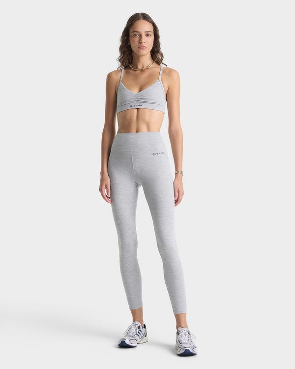 Woman wearing a gray sports bra and leggings on a white background