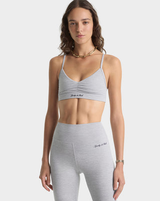 Woman wearing a gray sports bra and leggings set on a white background