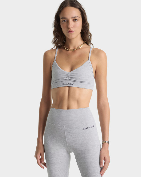 Woman wearing a gray sports bra and leggings set on a white background