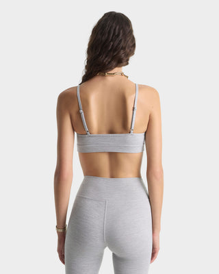 Woman wearing a gray sports bra and leggings on a light gray background