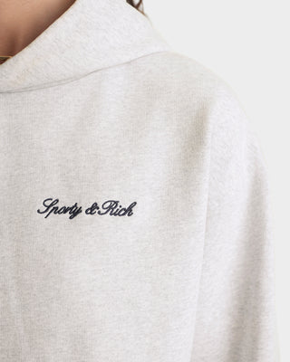 Close-up of a gray sweatshirt with 'Sporty & Rich' embroidery on a white background