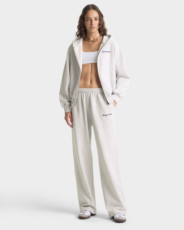 Woman wearing a light gray tracksuit with 'Dior' branding on a white background