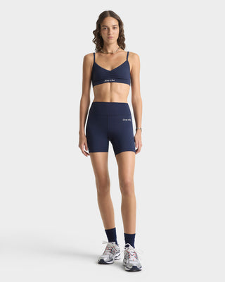 Woman wearing navy athletic bra and shorts on a white background