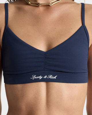 Navy blue sports bra with 'Sporty & Rich' logo on a white background