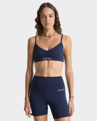 Woman wearing a navy blue sports bra and shorts set on a white background