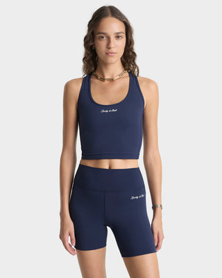 Woman wearing a navy blue sports bra and shorts set on a white background