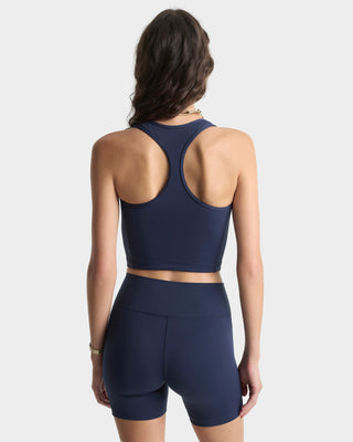 Woman wearing a navy blue sports bra and shorts set on a light gray background