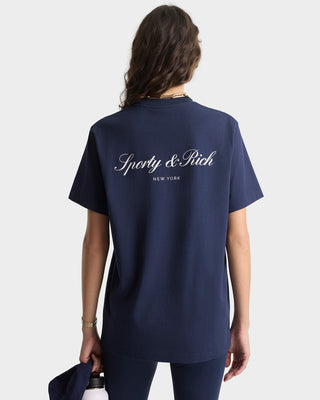 Person wearing a navy blue t-shirt with 'Sporty & Rich New York' text on the back, on a white background