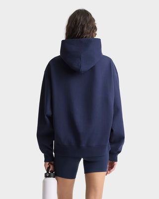 Person wearing a navy blue hoodie and shorts on a white background
