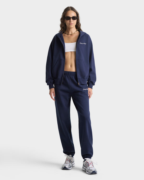 Woman wearing a navy tracksuit with 'The North Face' logo on a white background