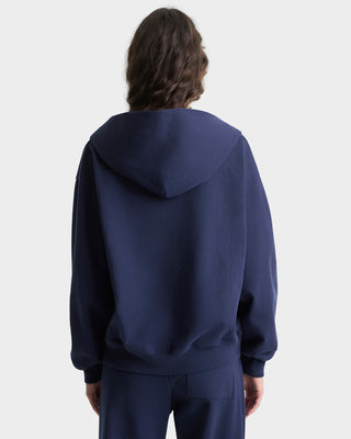 Person wearing a navy blue hoodie and pants on a white background