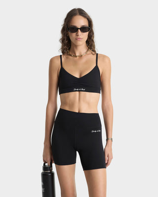 Woman wearing a black sports bra and shorts with 'Body by Rob' branding, holding a black water bottle on a white background.