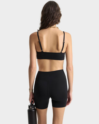 Person wearing a black sports bra and shorts on a white background