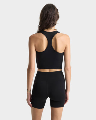 Person wearing a black sports bra and shorts set on a white background