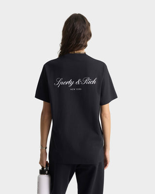 Person wearing a black t-shirt with 'Sporty & Rich' branding on the back, holding a water bottle.