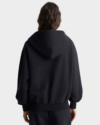 Person wearing a black hoodie from behind on a light gray background