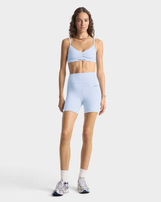 Woman wearing a light blue sports bra and shorts set on a white background