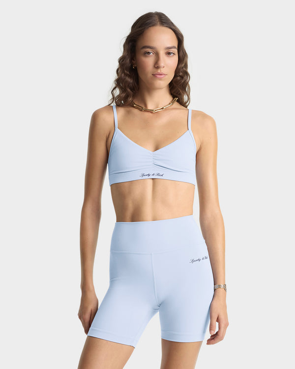 Woman wearing a light blue sports bra and shorts set on a white background