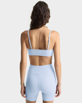 Woman wearing a light blue sports bra and shorts set on a white background