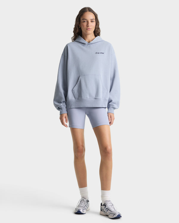 Person wearing a light blue hoodie and shorts on a white background