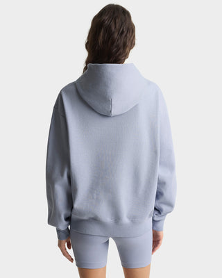 Person wearing a light blue hoodie and shorts set on a white background