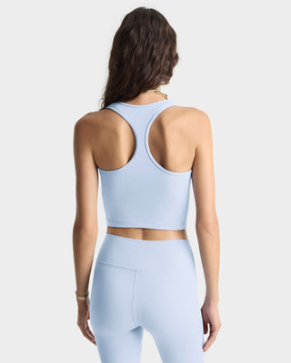 Woman wearing a light blue sports bra and leggings on a white background