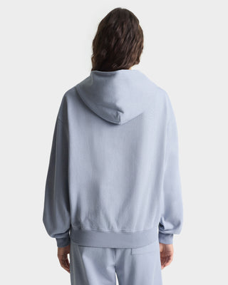 Person wearing a light gray hoodie and pants on a white background