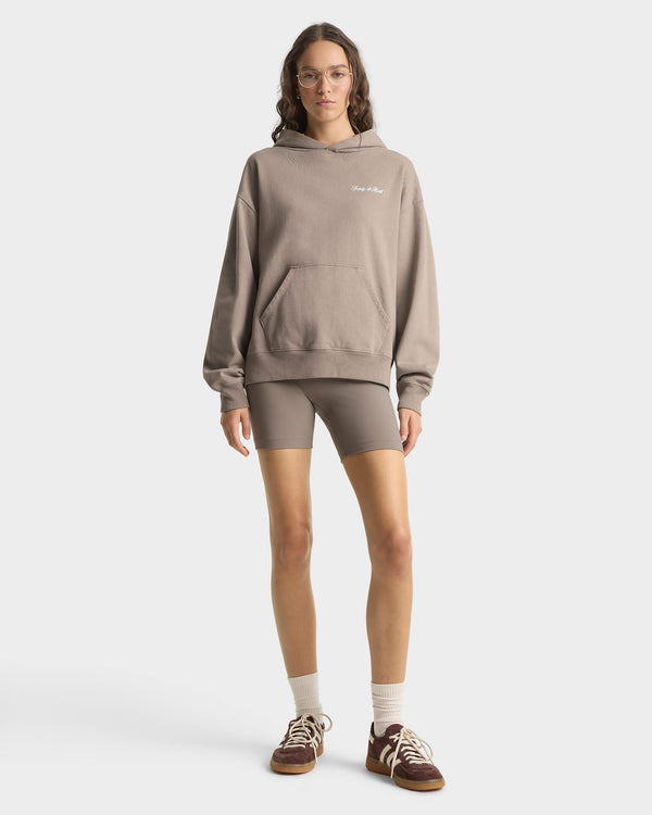 Person wearing a beige hoodie and shorts on a white background