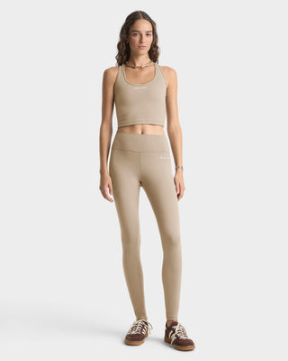 Woman wearing a beige athletic outfit on a white background