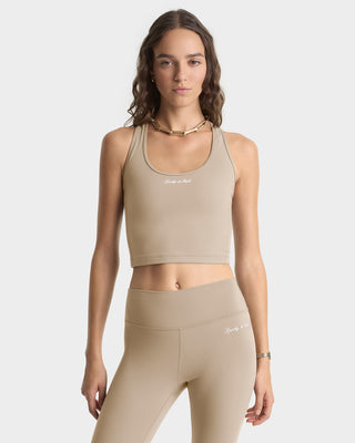 Woman wearing a beige sports bra and leggings set on a white background