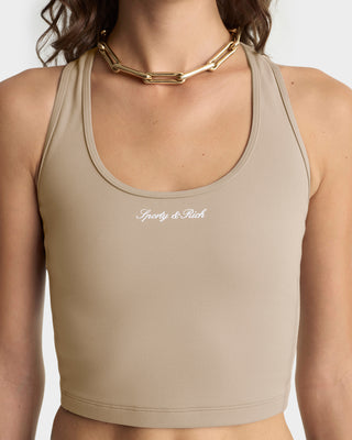 Beige sports bra with 'Sporty & Rich' logo worn by a person on a white background