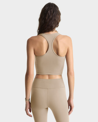Woman wearing a beige sports bra and leggings on a light gray background