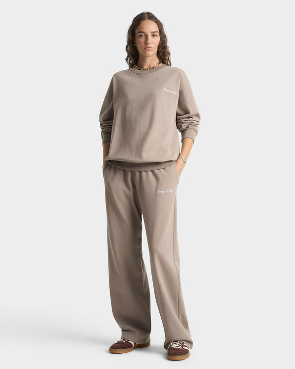 Woman wearing a beige sweatshirt and pants set on a white background