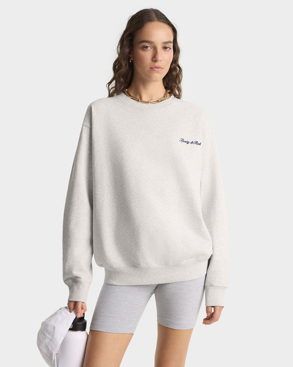 Woman wearing a light gray sweatshirt with a logo on a white background
