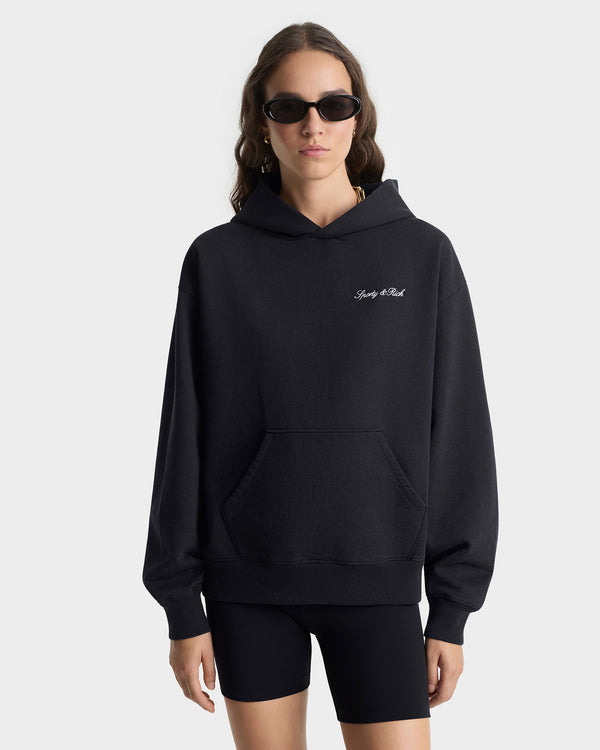 Person wearing a black hoodie with a brand logo on a white background