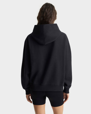 Person wearing a black hoodie and shorts on a white background