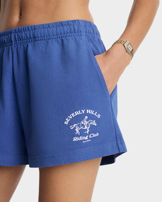 Blue shorts with 'Beverly Hills Riding Club' logo worn by a person.