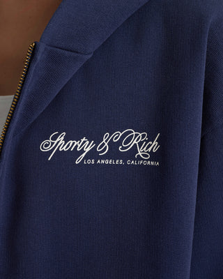 Navy blue jacket with 'Sporty & Rich' logo on a blurred background